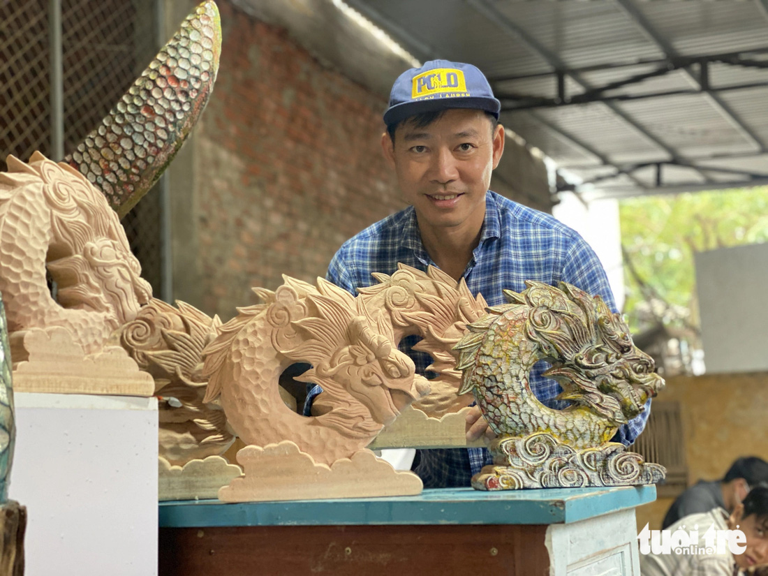Nghệ nhân Lê Ngọc Thuận với các linh vật rồng từ gỗ - Ảnh: B.D.