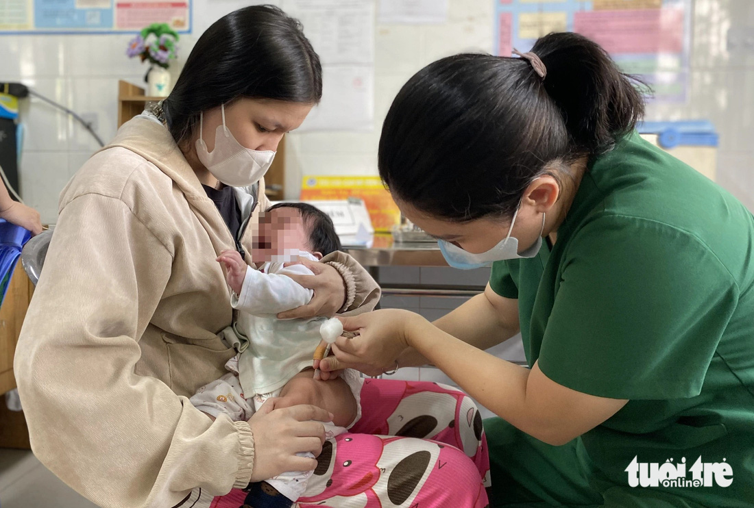 Chị L.H.N.P. (23 tuổi, ngụ xã Phú Xuân, huyện Nhà Bè) không giấu được niềm vui khi vắc xin 5 trong 1 về Trạm y tế xã Phú Xuân kịp thời, trước khi chị tính toán cho con tiêm dịch vụ - Ảnh: XUÂN MAI