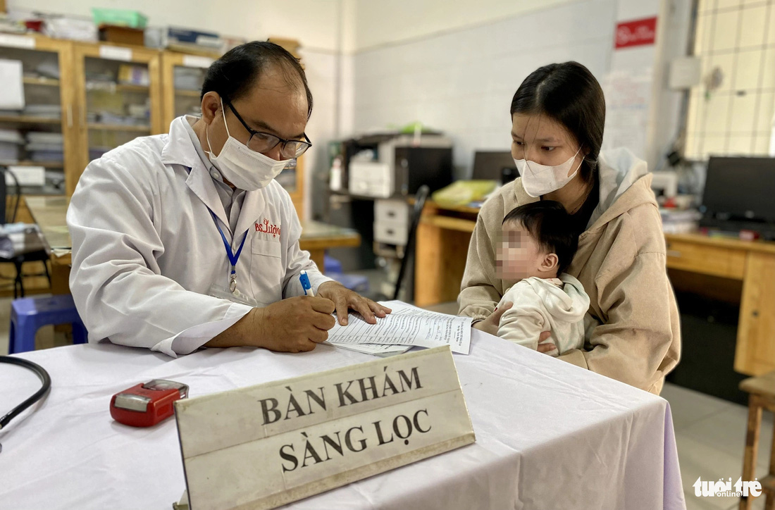 Bác sĩ Đào Văn Lượng - trưởng khoa kiểm soát bệnh tật Trung tâm Y tế huyện Nhà Bè - được tăng cường về Trạm y tế xã Phú Xuân để khám sàng lọc cho trẻ trước và sau tiêm - Ảnh: XUÂN MAI