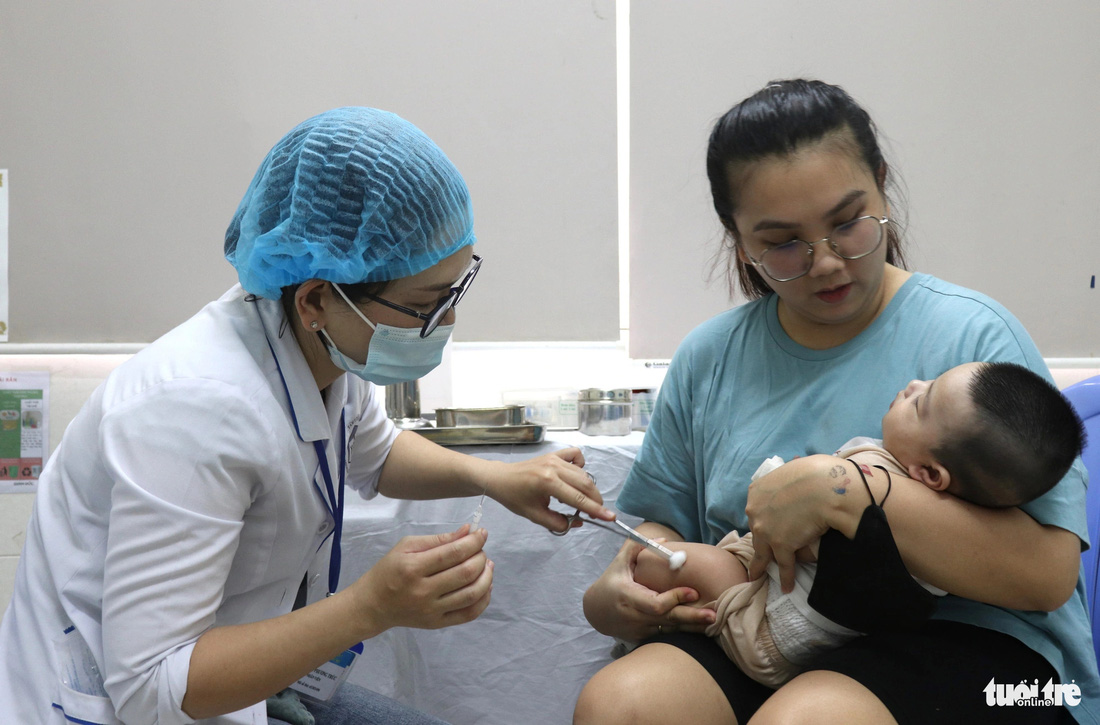 Trẻ được phụ huynh đưa đến Trạm y tế phường Phú Mỹ (quận 7) tiêm vắc xin sau khi được rà soát, gọi điện thoại gọi mời - Ảnh: XUÂN MAI