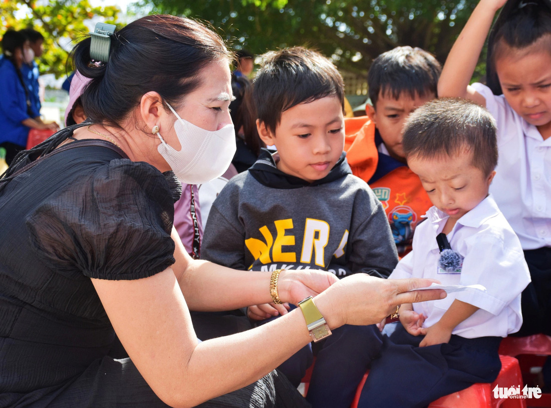 Em Mai Thanh Sang (Trường tiểu học Xuân Sơn) nhận phiếu quà từ chương trình, dù đã học đến lớp 3 nhưng thân hình em nhỏ bé như trẻ 1 tuổi - Ảnh: TRẦN HOÀI