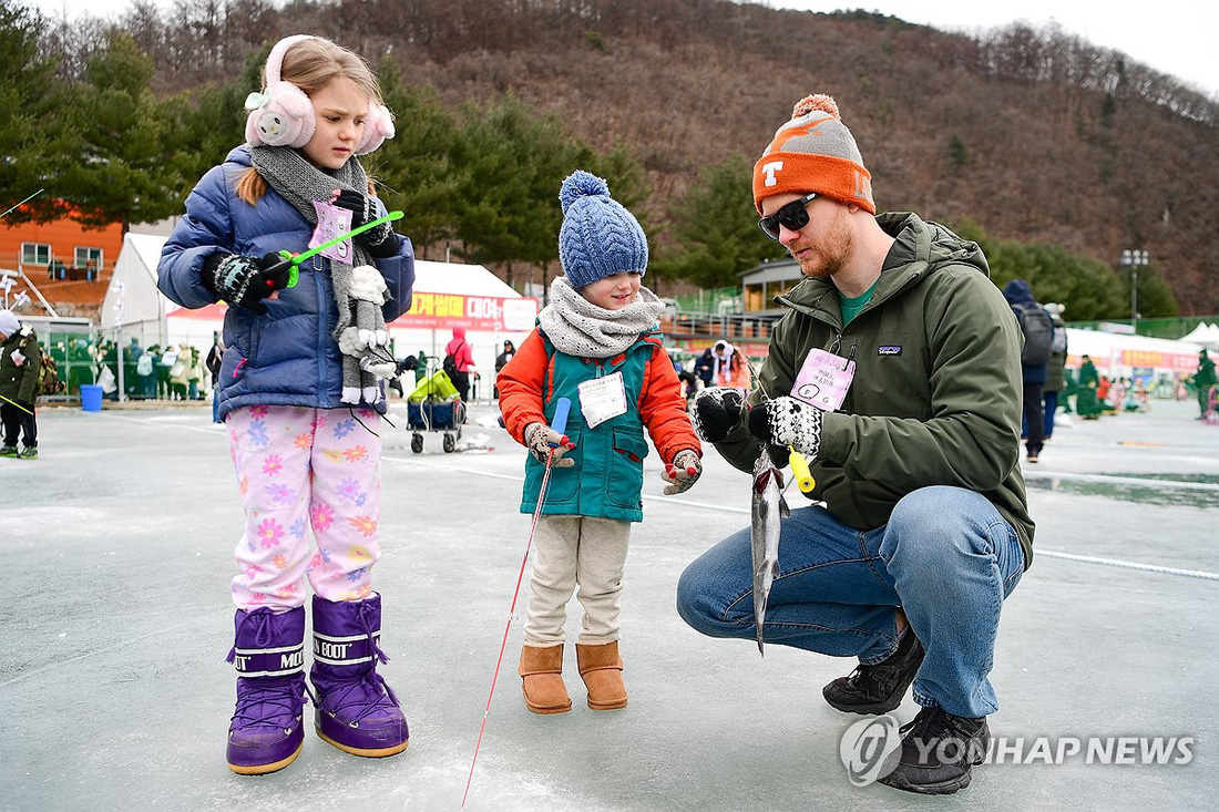 Một gia đình người nước ngoài vui mừng khi câu được cá tại lễ hội câu cá sông băng Hwacheon Sancheoneo 2024 - Ảnh: YONHAP