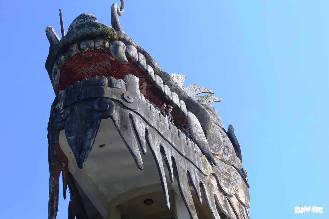Hai du khách nước ngoài đứng trên miệng chú rồng khổng lồ ở Huế - Ảnh: N.L.