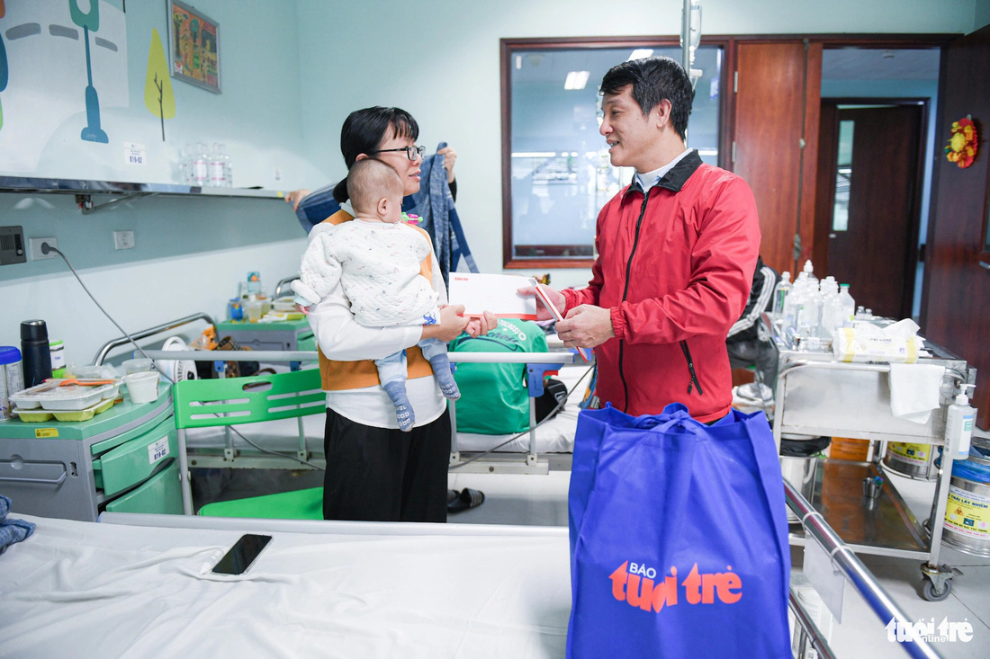 Nhà báo Nguyễn Đức Bình - phó trưởng văn phòng đại diện báo Tuổi Trẻ tại Hà Nội - tặng quà cho gia đình bệnh nhi - Ảnh: NAM TRẦN