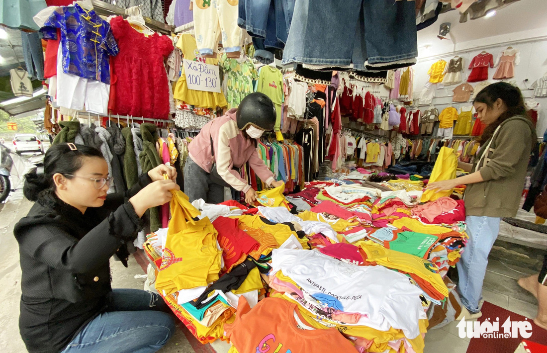 Một cửa hàng bán áo quần trẻ em ở chợ thương mại Tam Kỳ chỉ lác đác khách. Trong ảnh là 2 nhân viên và chỉ một khách (đội mũ bảo hiểm) lựa mua hàng - Ảnh: LÊ TRUNG