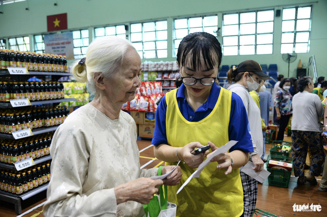 Chị Thanh (bên phải) nhân viên siêu thi 0 đồng hướng dẫn người lớn tuổi mua hàng.