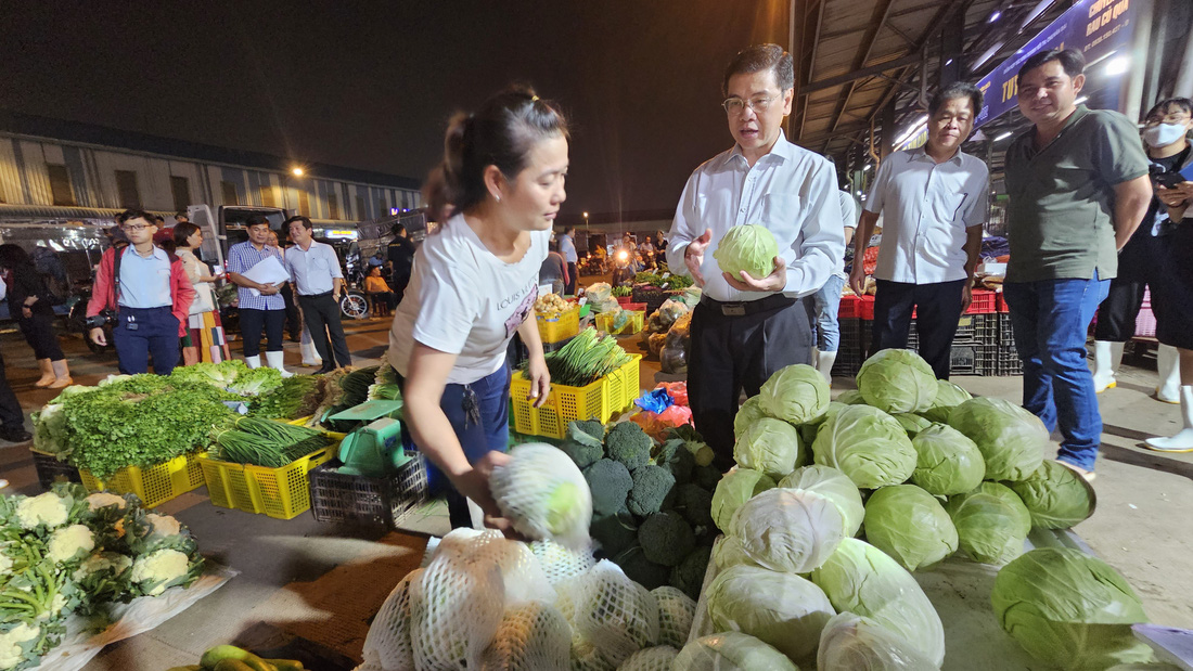 Phó chủ tịch UBND TP.HCM Nguyễn Văn Dũng trao đổi với thương nhân tại chợ Bình Điền về giá cả và nguồn cung hàng Tết vào khuya 25-1 - Ảnh: N.TRÍ