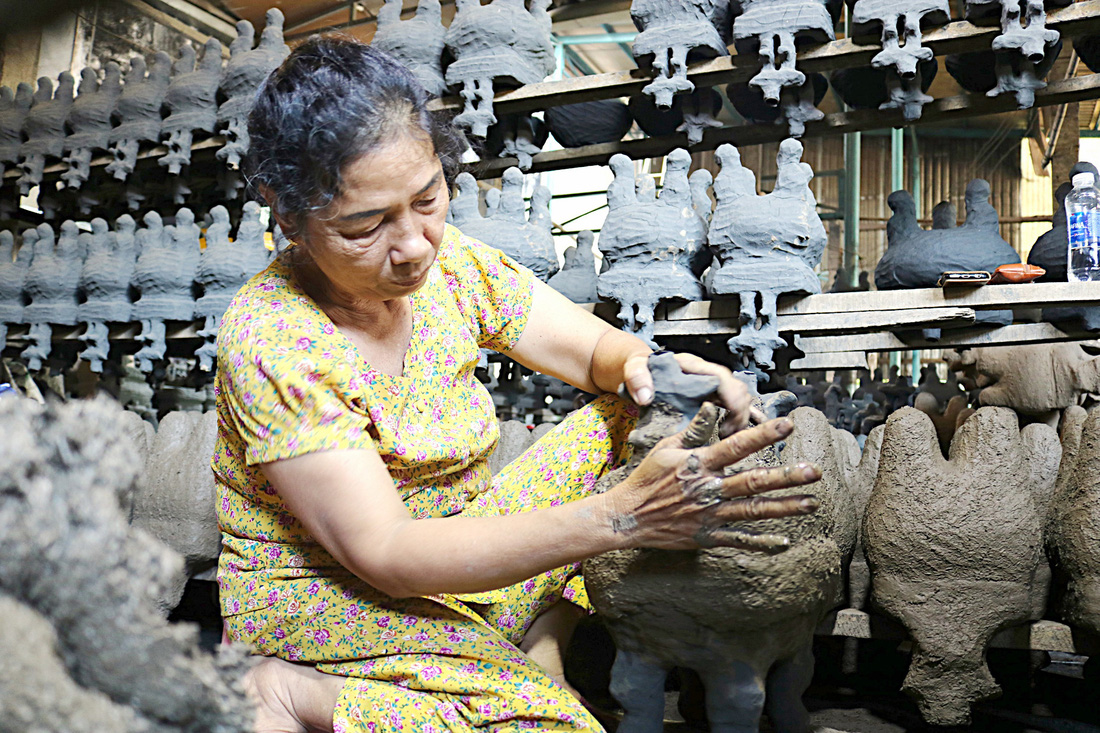 Bà Tư (63 tuổi), thợ lành nghề gần 40 năm tại cơ sở lư đồng Năm Toàn, đang áo vỏ khuôn bằng hỗn hợp đất sét và trấu trước khi đưa vào lò nung