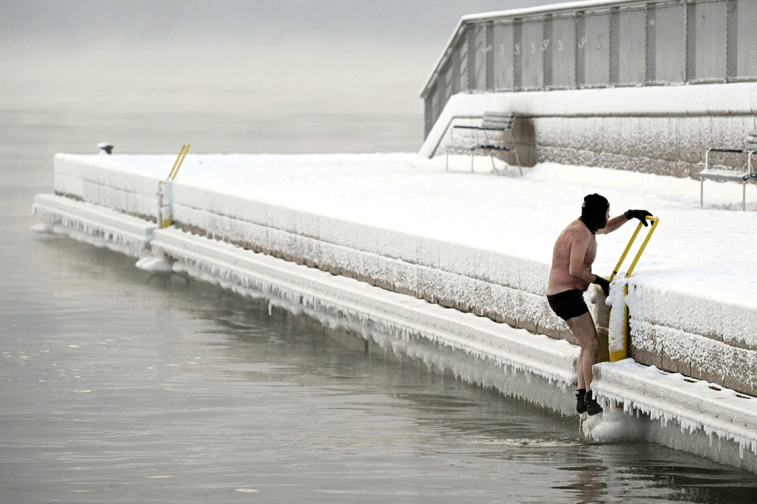 Một người đàn ông leo lên bờ từ nước biển lạnh giá ở thủ đô Helsinki, Phần Lan ngày 2-1 - Ảnh: REUTERS