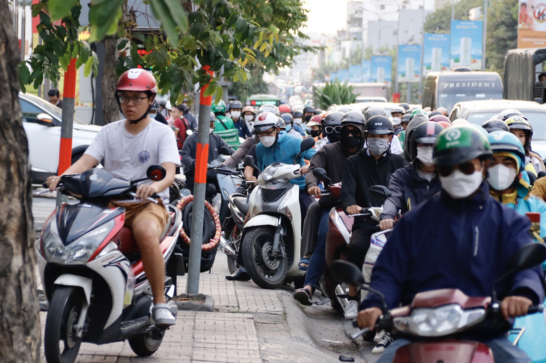 Nhiều người sốt ruột bất chấp leo lên lề để đi vì kẹt xe dài và lâu - Ảnh: TIẾN QUỐC