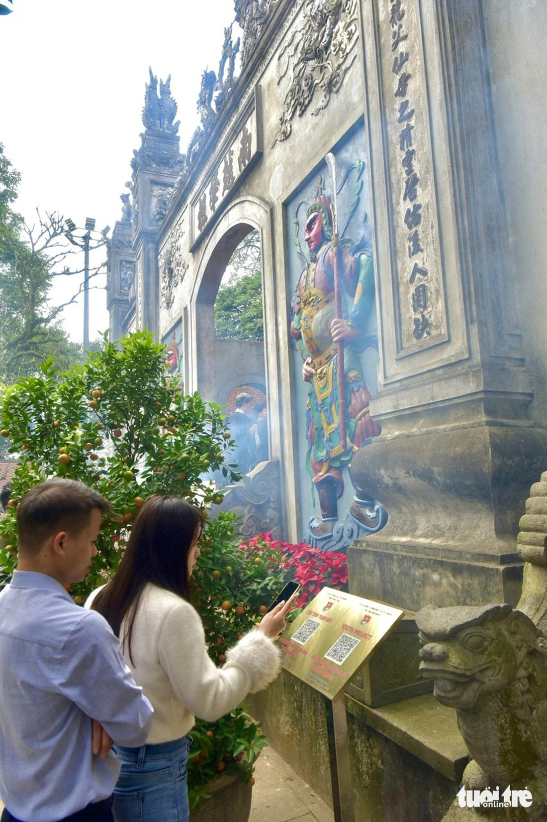 Vợ chồng chị Hảo (thị xã Phú Thọ, tỉnh Phú Thọ) quét mã để tìm hiểu thêm về thông tin di tích tại đền Thượng - Ảnh: T.T.D.