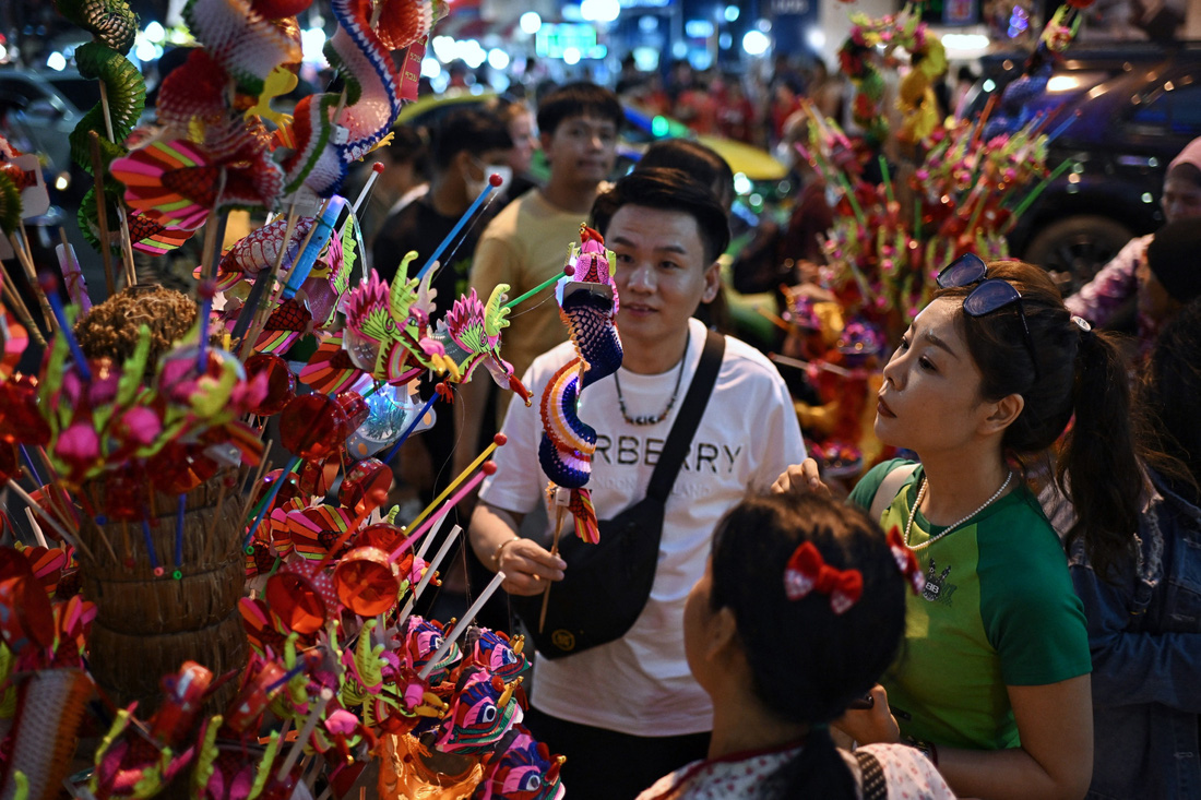 Người bán hàng rong trên đường phố Bangkok bày bán những món đồ chơi hình rồng trong đêm 30, rạng sáng mùng 1 Tết - Ảnh: AFP