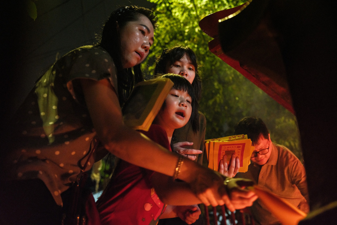 Một gia đình tại thủ đô Jakarta, Indonesia hóa vàng ở ngôi chùa nhỏ gần nhà vào rạng sáng mùng 1 Tết - Ảnh: AFP