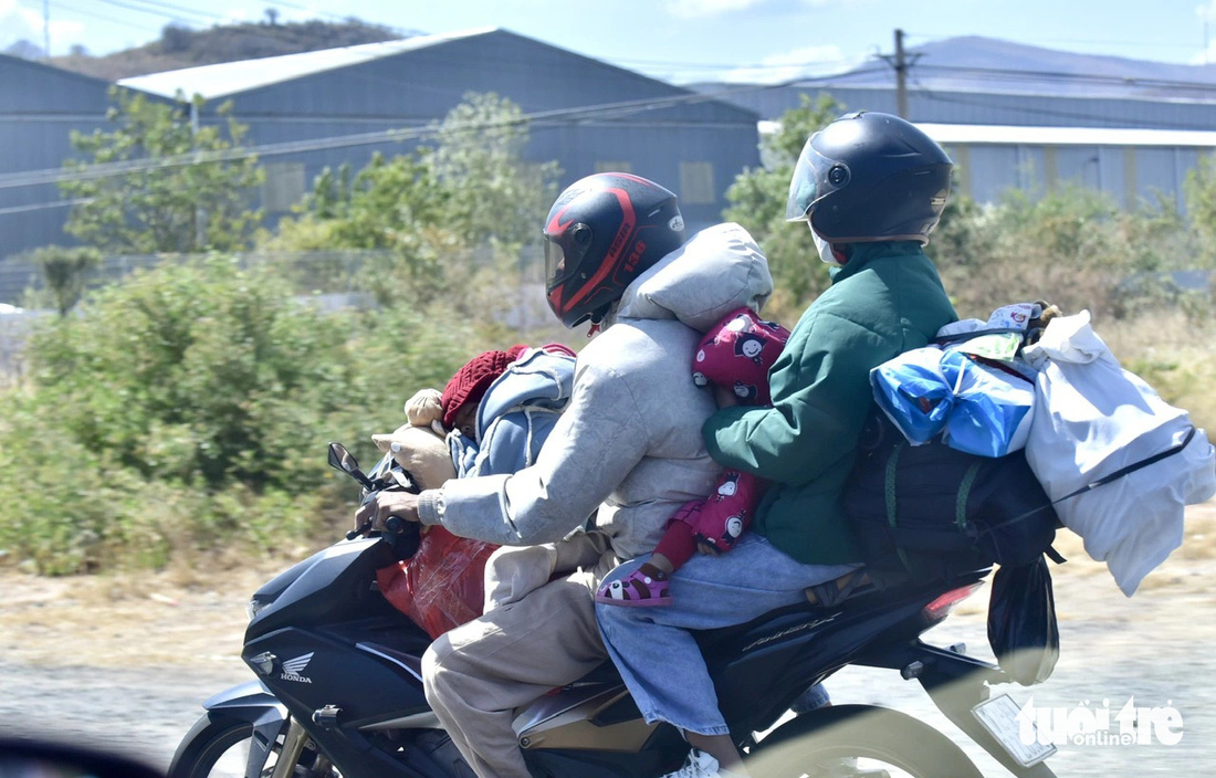 Hai đứa trẻ ngủ say sưa khi được ba mẹ chở trên xe máy trở về nhà sau khi ăn Tết ở quê. Ảnh chụp đoạn qua Ninh Thuận chiều mùng 6 Tết (ngày 15-2) - Ảnh: T.T.D.