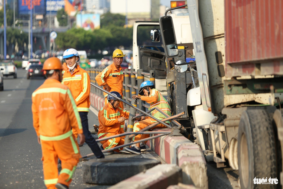 Công nhân cầu đường đang dọn dẹp hiện trường, một bánh xe container bị văng ra - Ảnh: MINH HÒA
