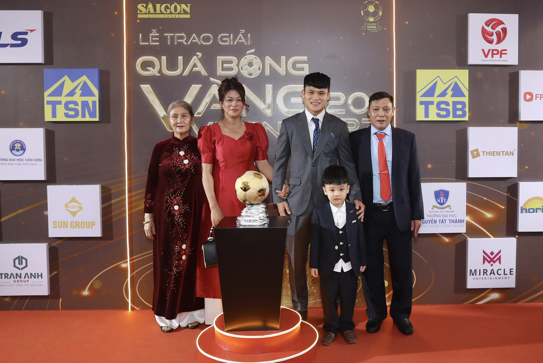 Gia đình tuyển thủ Phạm Tuấn Hải bên cạnh mô hình Quả bóng vàng - Ảnh: QUANG THỊNH