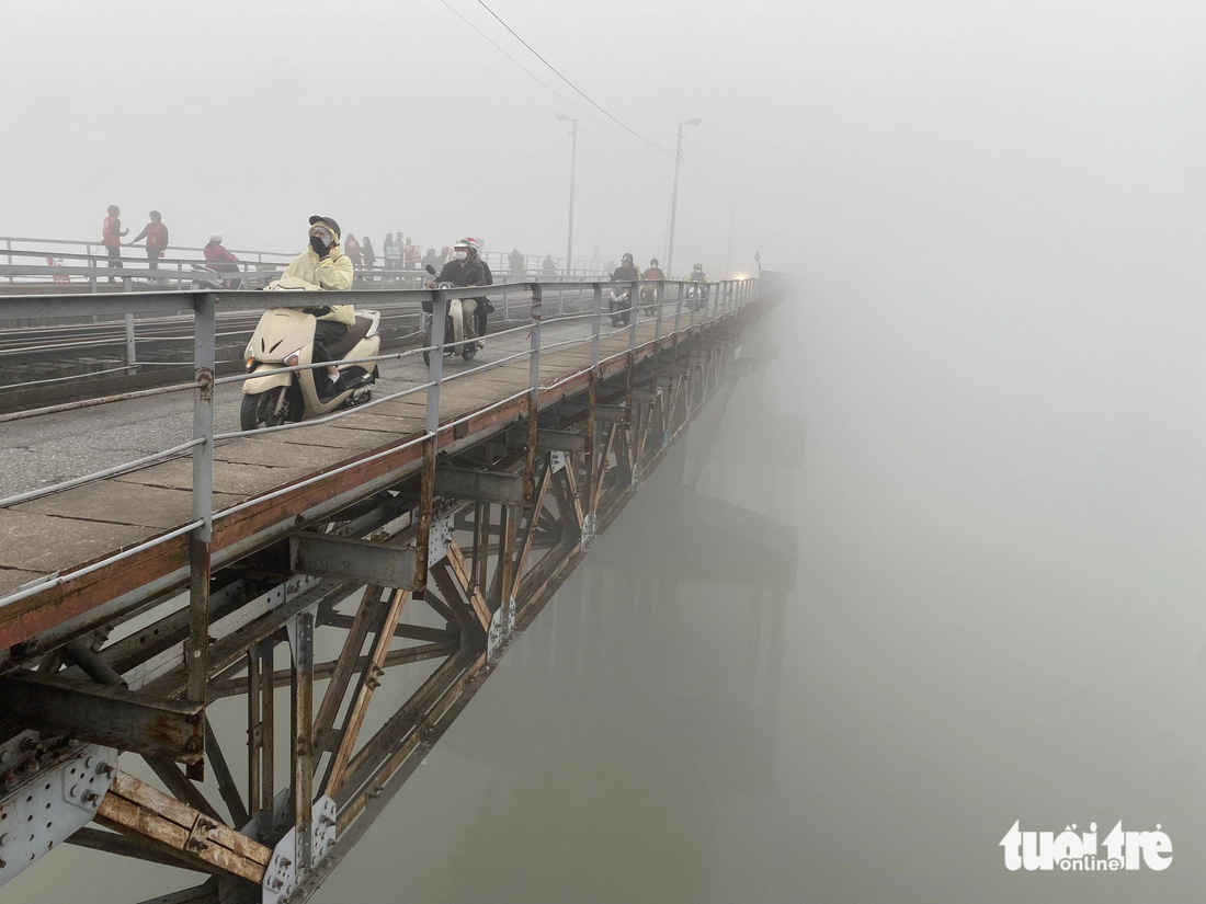 Trên cầu Long Biên tầm nhìn giảm do sương mù, dù 9h sáng nhưng xe máy vẫn phải bật đèn lưu thông - Ảnh: NGUYÊN BẢO