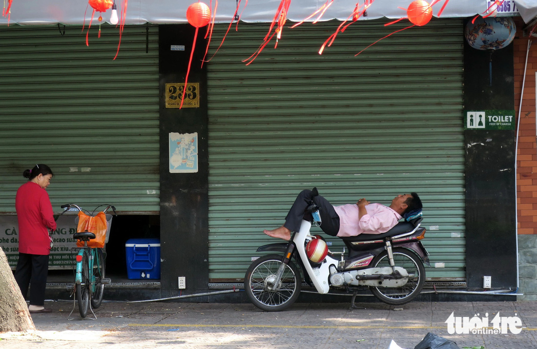 Một bác tài xe ôm nghỉ trưa trước hiên một quán hàng trên đường Trường Sa, quận 1.