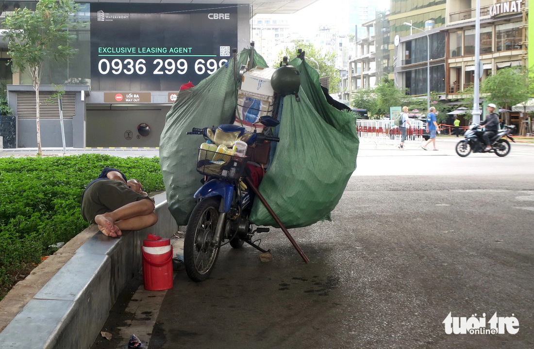 Một người thu mua, lượm ve chai nghỉ trưa dưới da cầu tránh nóng ở quận 1