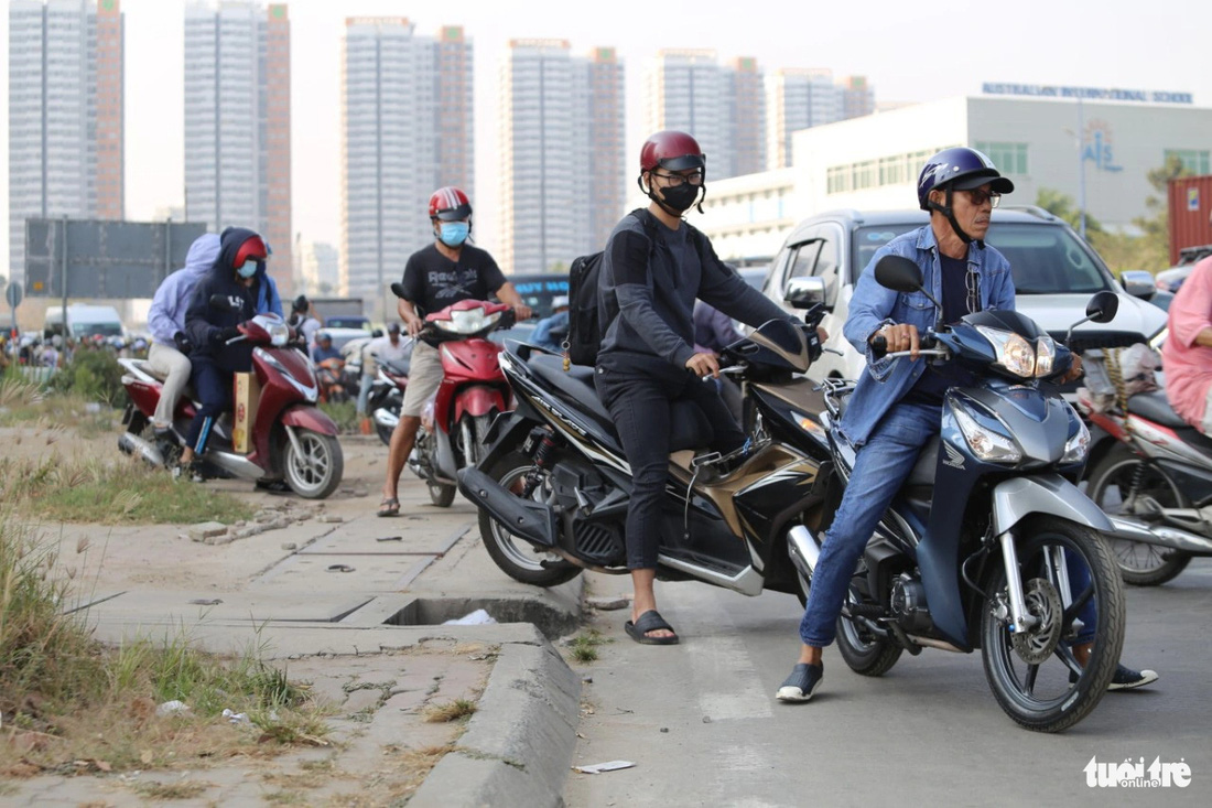 Người đi xe máy phải leo lên vỉa hè để chạy vì bị các xe ô tô lấn hết - Ảnh: MINH HÒA