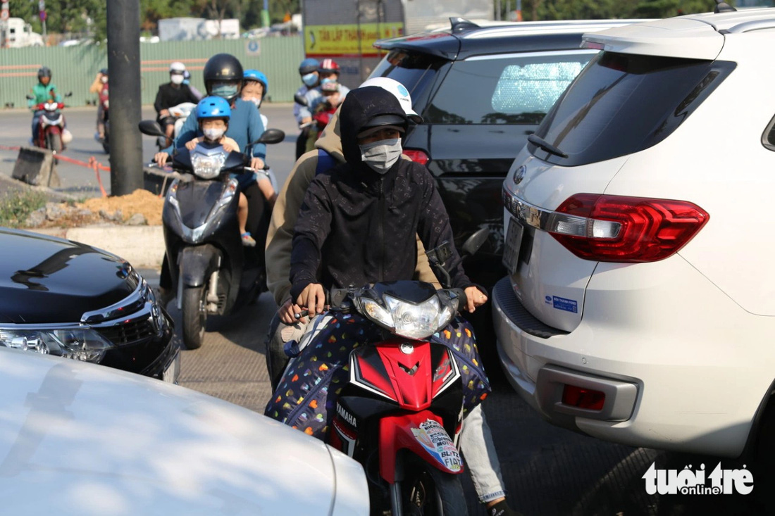 Xe máy len lỏi vào dòng xe đang kẹt tại giao lộ Mai Chí Thọ - đường dẫn cao tốc - Ảnh: MINH HÒA