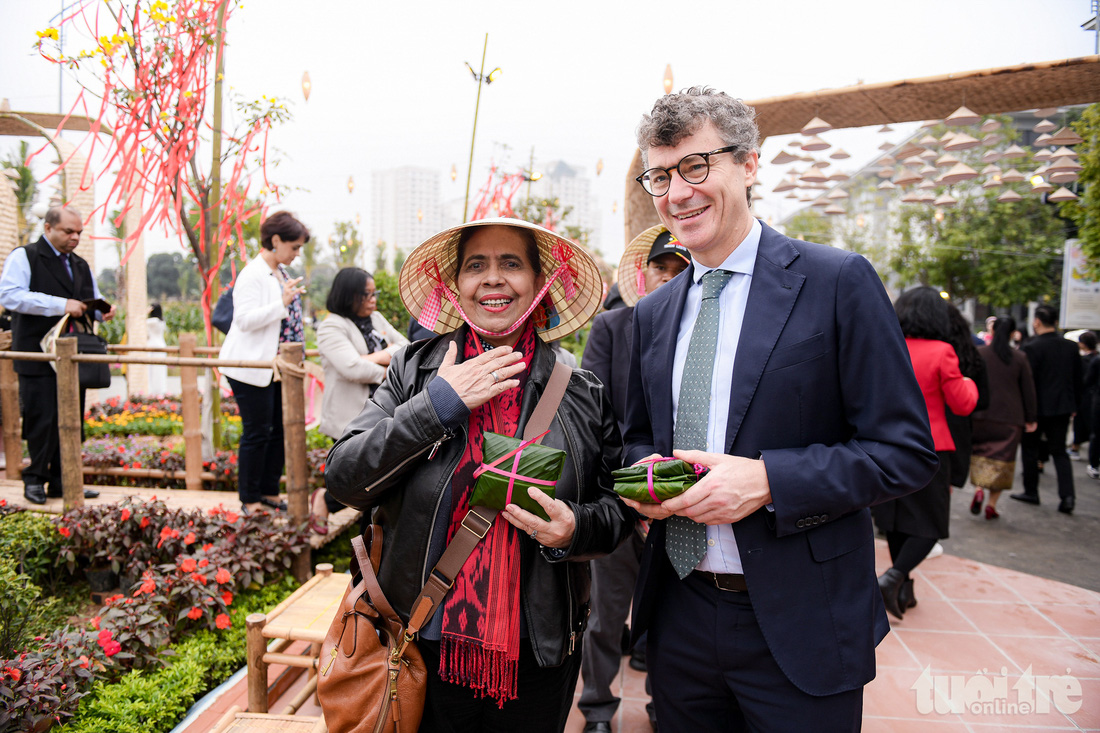 Những vị khách đầu tiên của đường hoa Home Hanoi Xuan 2024 thích thú với món quà bánh phu thê trong trải nghiệm Tết Việt tại lễ khai mạc - Ảnh: NAM TRẦN