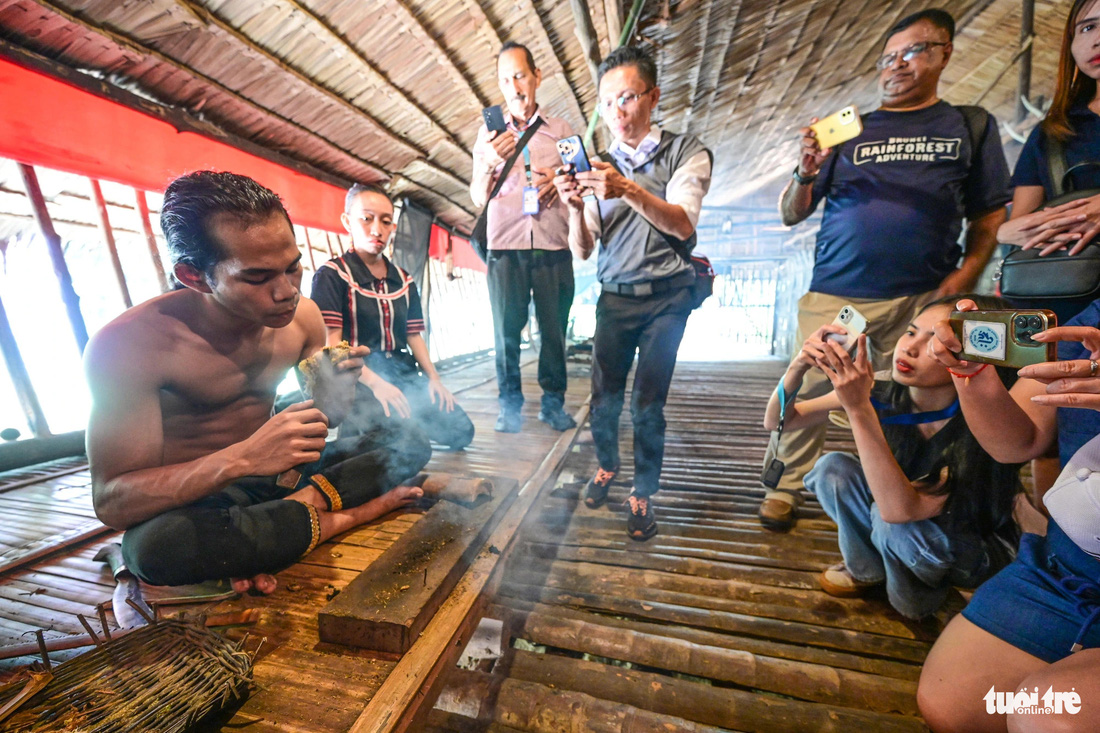 Du khách xem cách tạo ra lửa thời xưa của thanh niên làng văn hóa Mari Mari