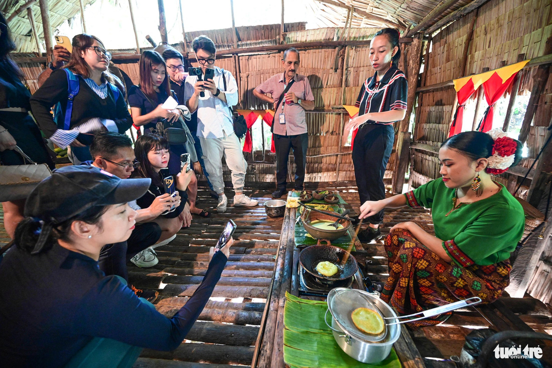 Du khách xem cách làm bánh của các thiếu nữ trong làng văn hóa Mari Mari