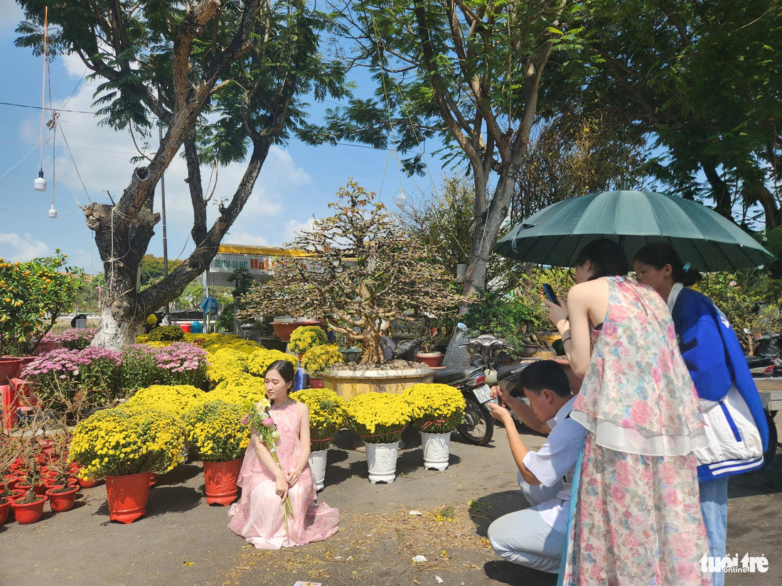 Trong lúc nhà vườn rầu vì hoa bán chậm, giới trẻ ra chợ hoa chụp hình lưu niệm những khoảnh khắc ngày xuân - Ảnh: BỬU ĐẤU