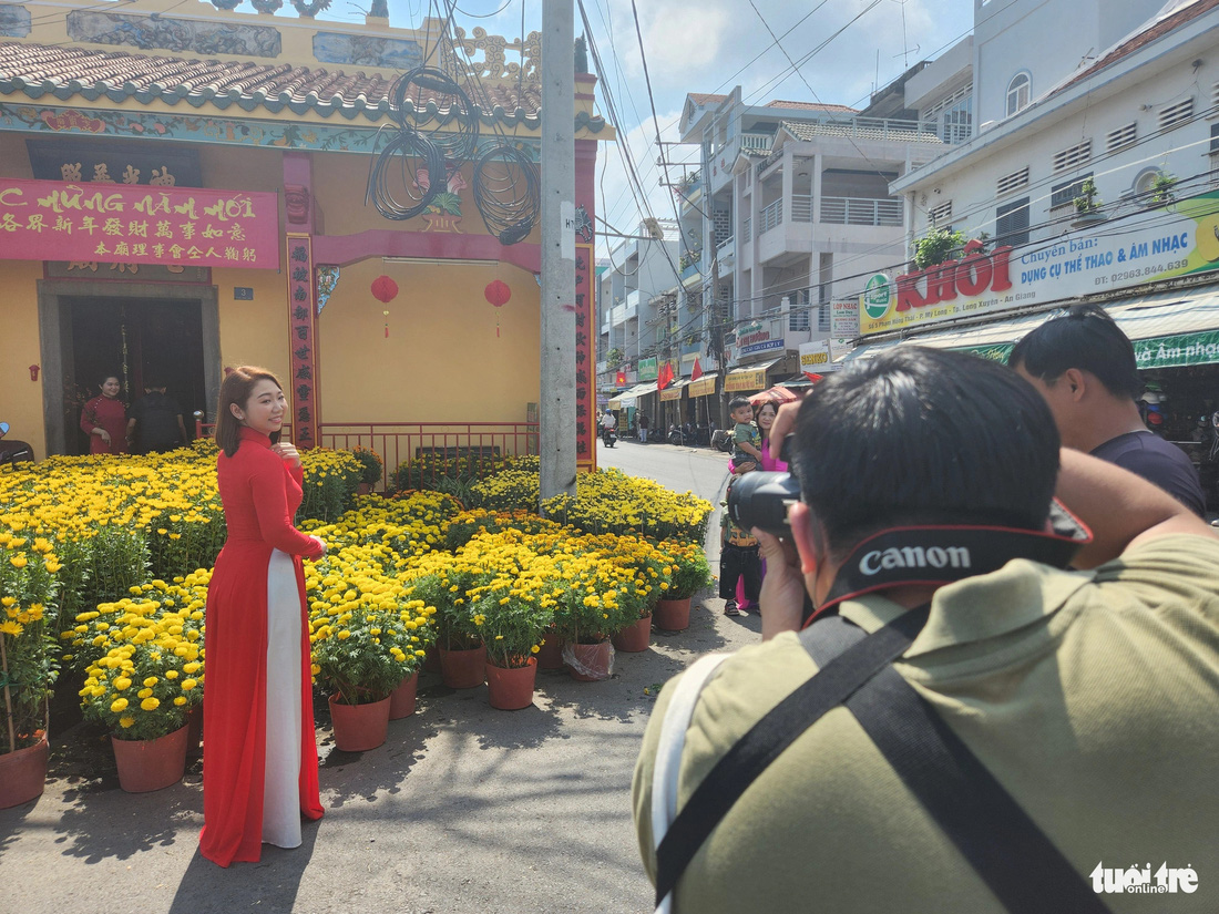 Giới trẻ diện áo dài chụp hình lưu niệm tại chợ hoa xuân đường Phạm Hồng Thái, phường Mỹ Long, TP Long Xuyên - Ảnh: BỬU ĐẤU