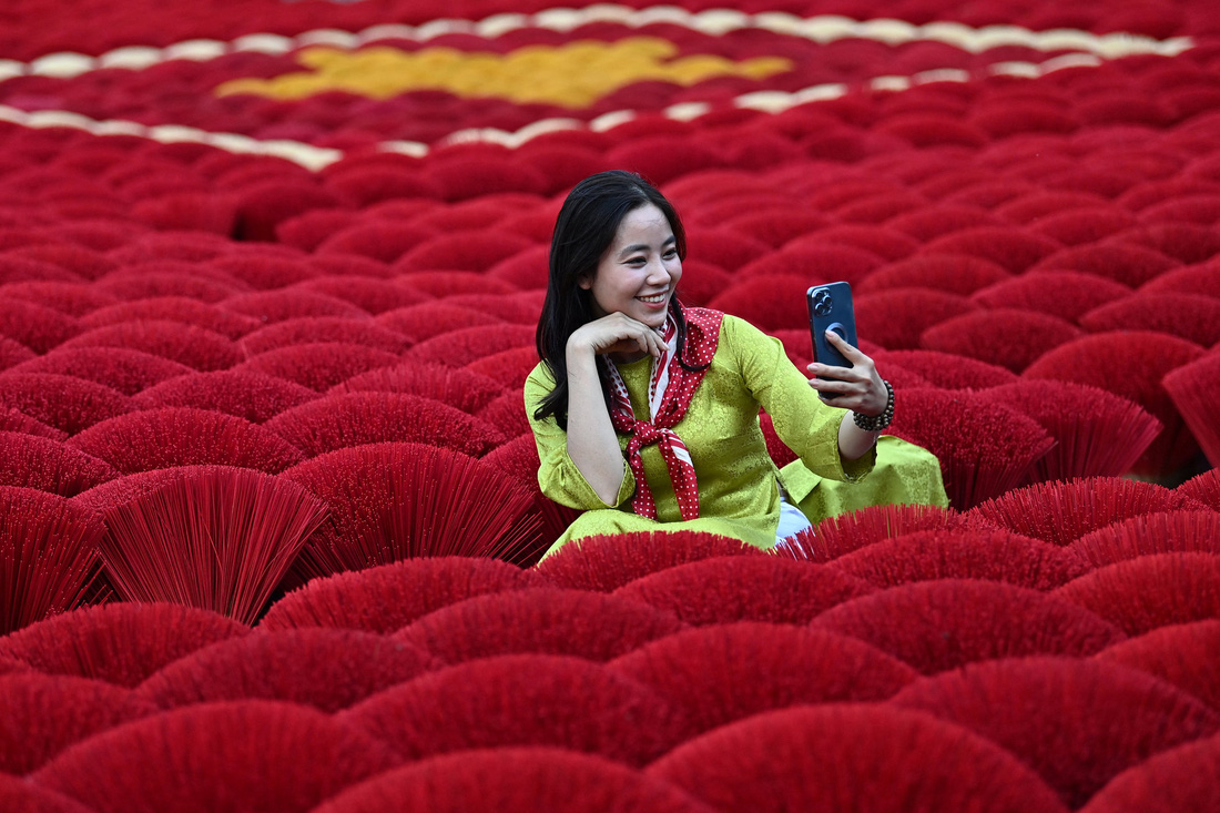 Du khách chụp ảnh selfie trước những bó hương xếp hình quốc kỳ Việt Nam ở làng Quảng Phú Cầu, ngoại thành Hà Nội, ngày 20-1 - Ảnh: AFP