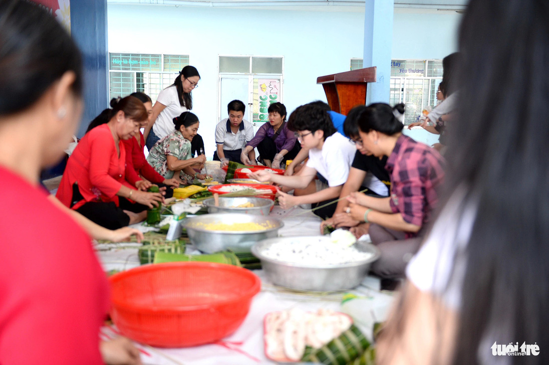 Phụ huynh và học sinh Trường Đinh Thiện Lý (quận 7) chung tay gói bánh tét làm quà tặng người nghèo - Ảnh: HẢI QUỲNH