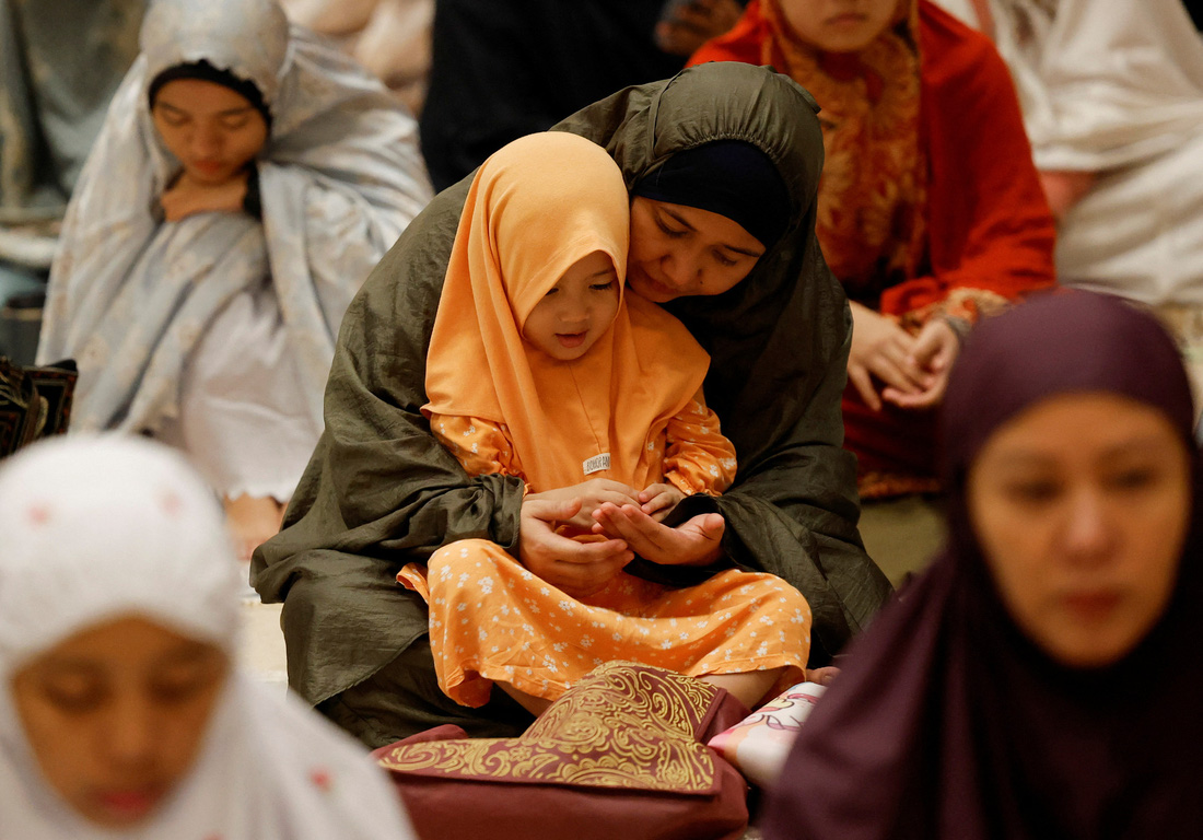 Người mẹ hướng dẫn con gái đọc kinh trong giờ kinh Tarawih đầu tiên của tháng Ramadan tại thánh đường Hồi giáo Istiqlal (Indonesia) hôm 11-3 - Ảnh: REUTERS