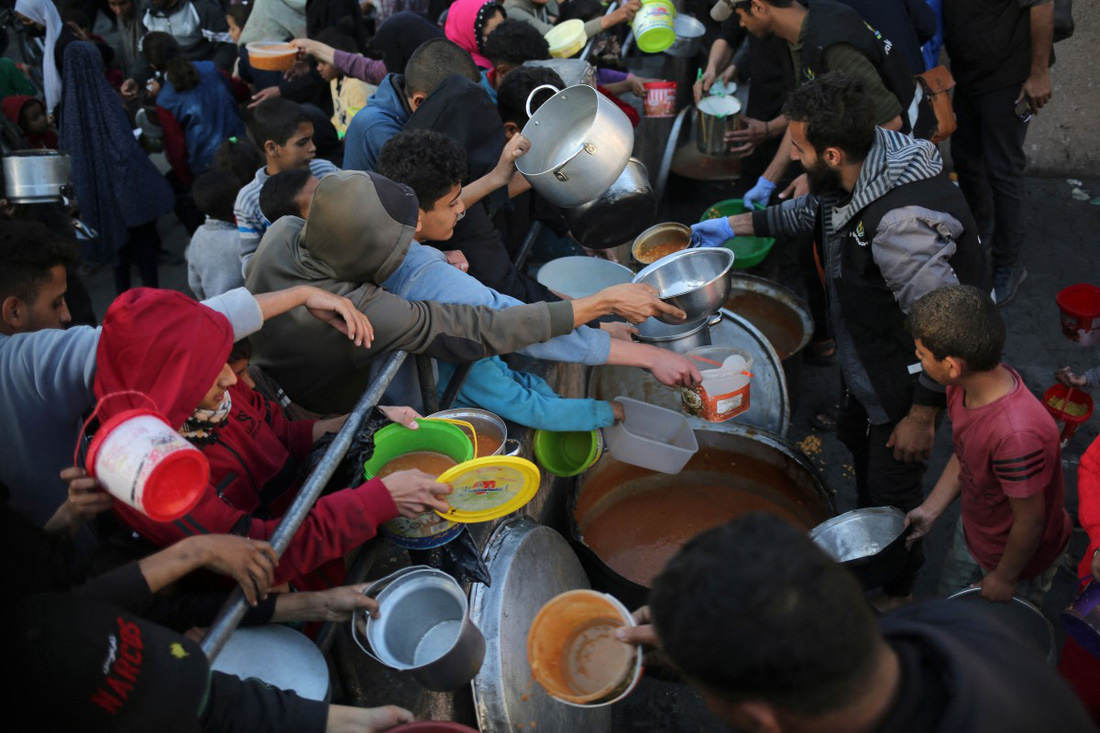 Đám đông chen lấn để nhận thức ăn cho bữa Iftar từ một tổ chức từ thiện ở thành phố Rafah - Ảnh: AFP
