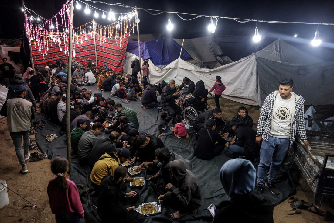 Những người Palestine đang ăn bữa Iftar tại một trại tị nạn dành cho người di tản ở thành phố Rafah, miền nam Dải Gaza tối 11-3 - Ảnh: AFP