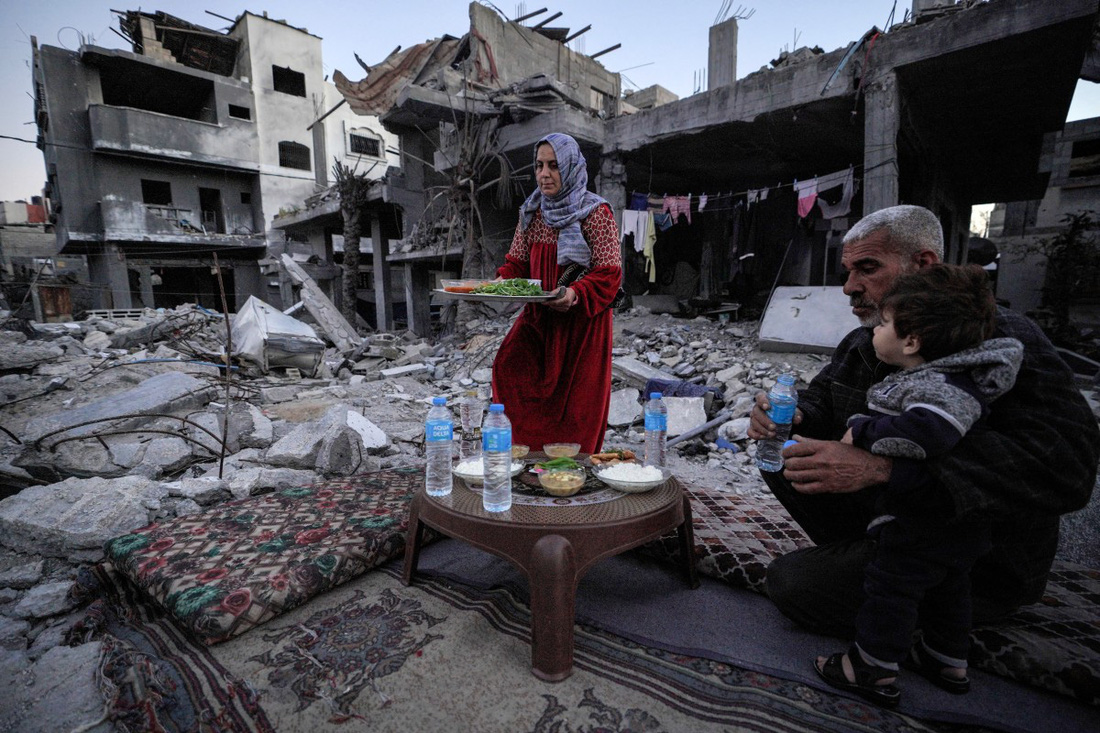 Gia đình ông Al-Naji chuẩn bị ăn bữa Iftar - tức bữa ăn sau một ngày dài nhịn ăn - giữa đống đổ nát ở Deir el-Balah, miền trung Dải Gaza - Ảnh: AFP