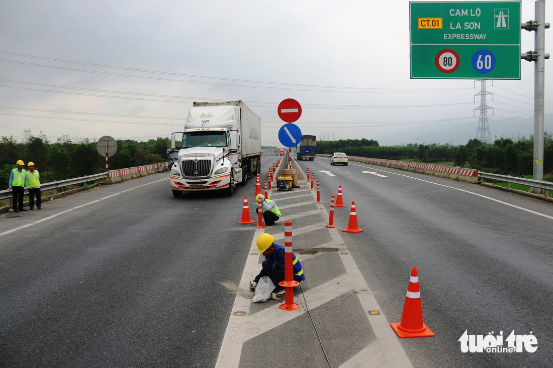 Các tốp công nhân thuộc Ban quản lý dự án đường Hồ Chí Minh thi công lắp trụ cảnh báo nguy hiểm trên cao tốc Cam Lộ - La Sơn - Ảnh: N.L.