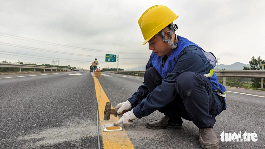 Công nhân lắp đinh phản quang trên vạch kẻ đường phân cách hai đoạn đường xe chạy trên cao tốc Cam Lộ - La Sơn - Ảnh: N.L.