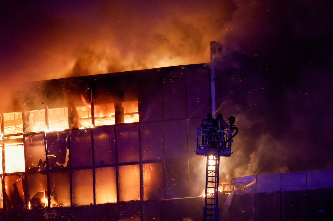 Lính cứu hỏa phun vòi rồng để dập tắt đám cháy trên tầng cao nhất của tòa nhà - Ảnh: REUTERS