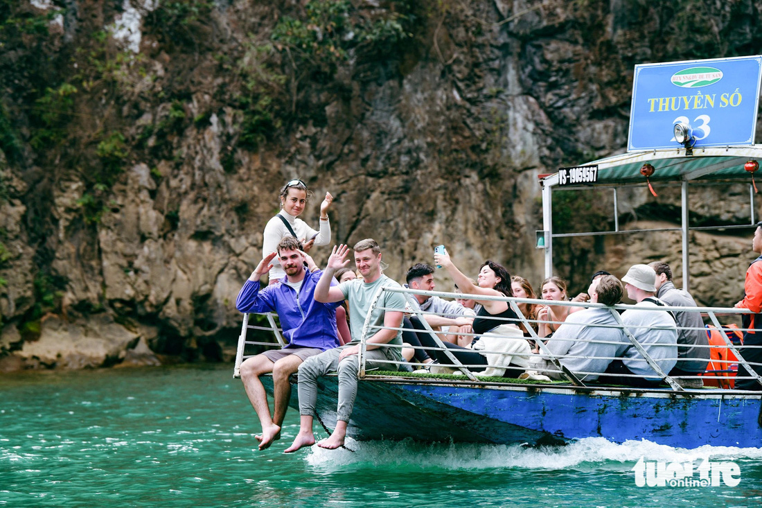 Du khách quốc tế đi thuyền trên sông Nho Quế giữa mùa hoa gạo