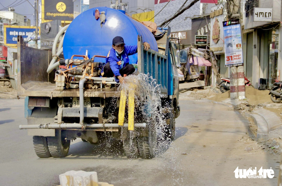 Đơn vị thi công tưới nước bề mặt đường Võ Văn Ngân nhằm giảm tình trạng cát bụi bay - Ảnh: TIẾN QUỐC