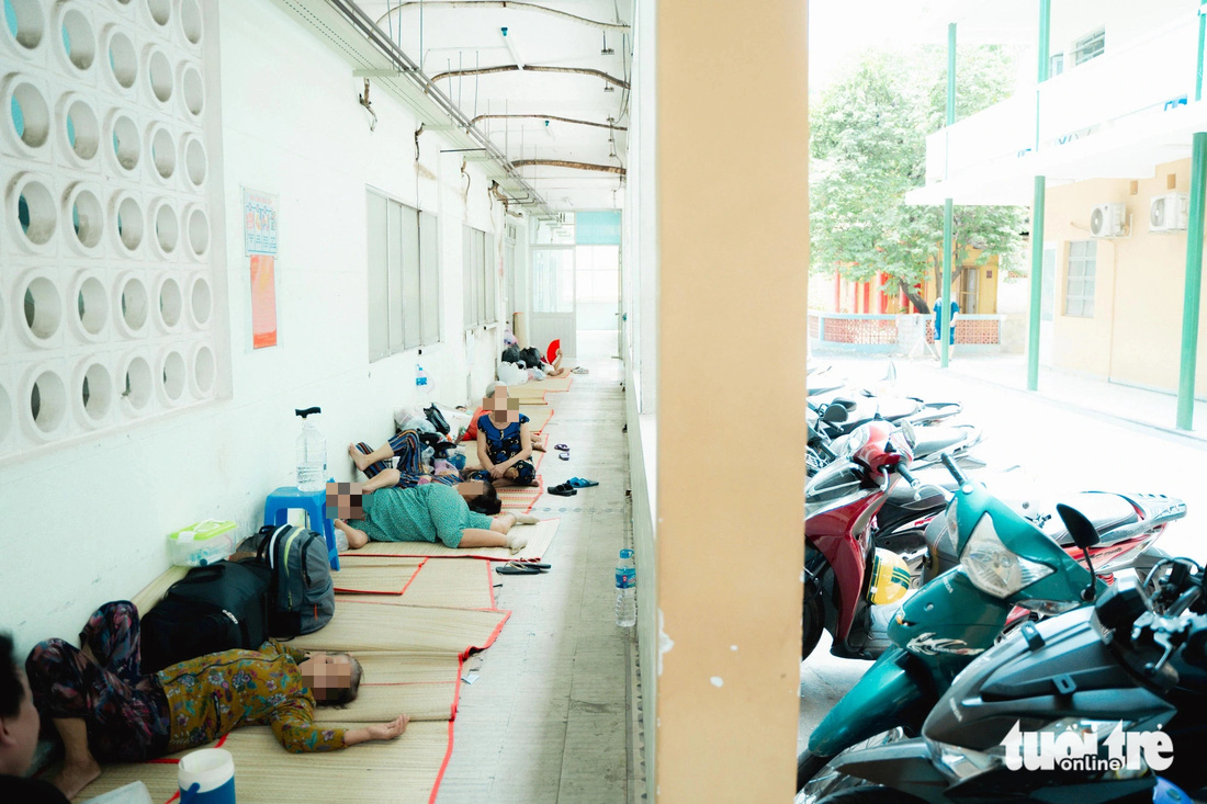 Nhiều người trải chiếu nằm tránh nắng ngay hành lang Bệnh viện Nguyễn Trãi (TP.HCM) - Ảnh: THANH HIỆP