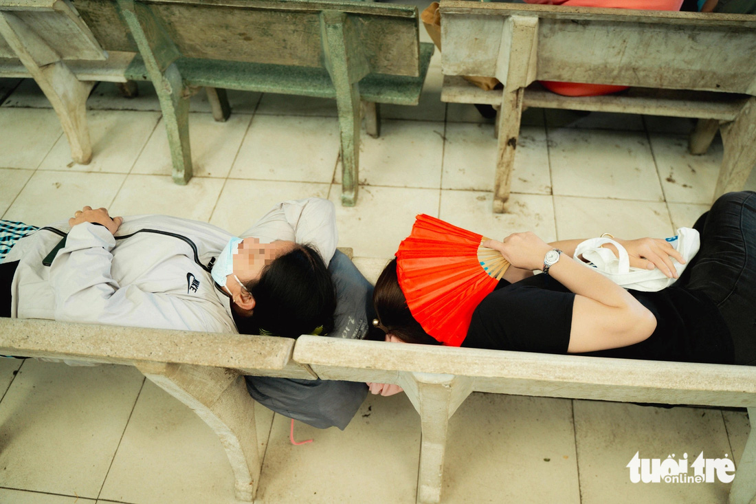 Người chăm bệnh nằm trên những chiếc ghế đá dưới các mái che của Bệnh viện Nguyễn Tri Phương để tránh nóng