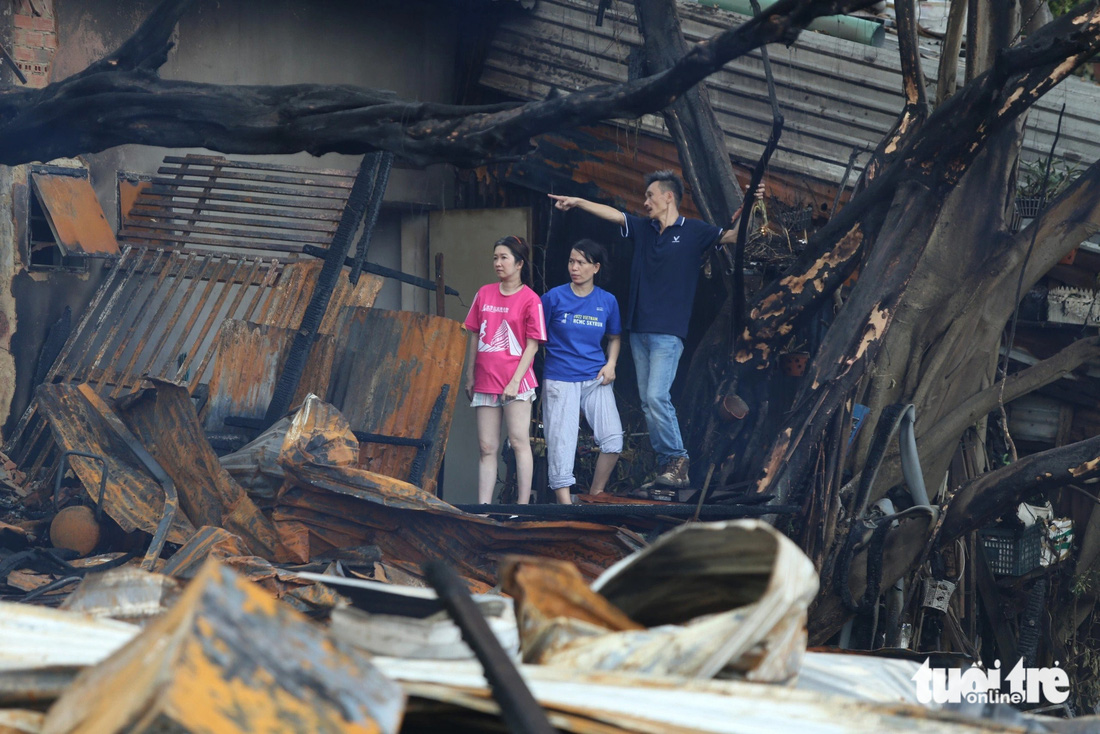 Hàng xóm nhà kế bên đi qua quan sát hiện trường các căn nhà bị cháy - Ảnh: MINH HÒA