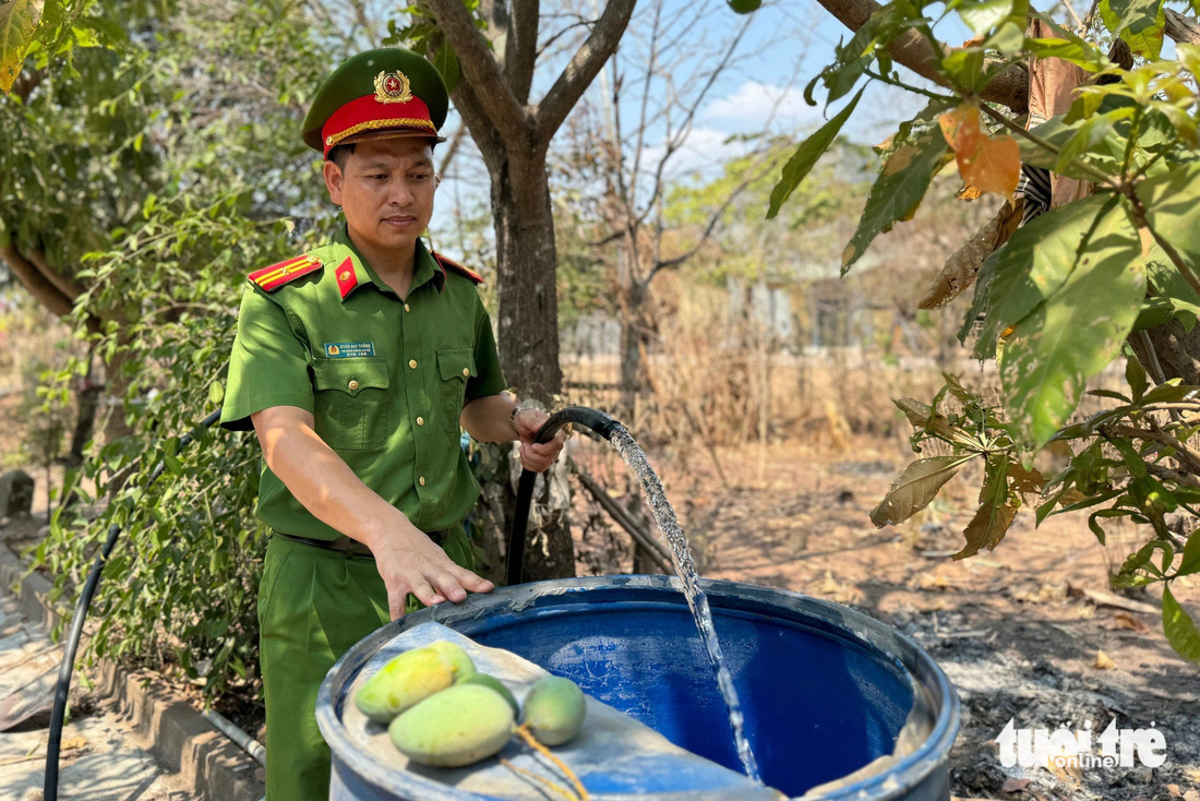 Thiếu tá Đoàn Huy Tưởng - trưởng Công an xã Ea R’Vê - tham gia đưa nước đến tận nhà cho người dân - Ảnh: TRUNG TÂN