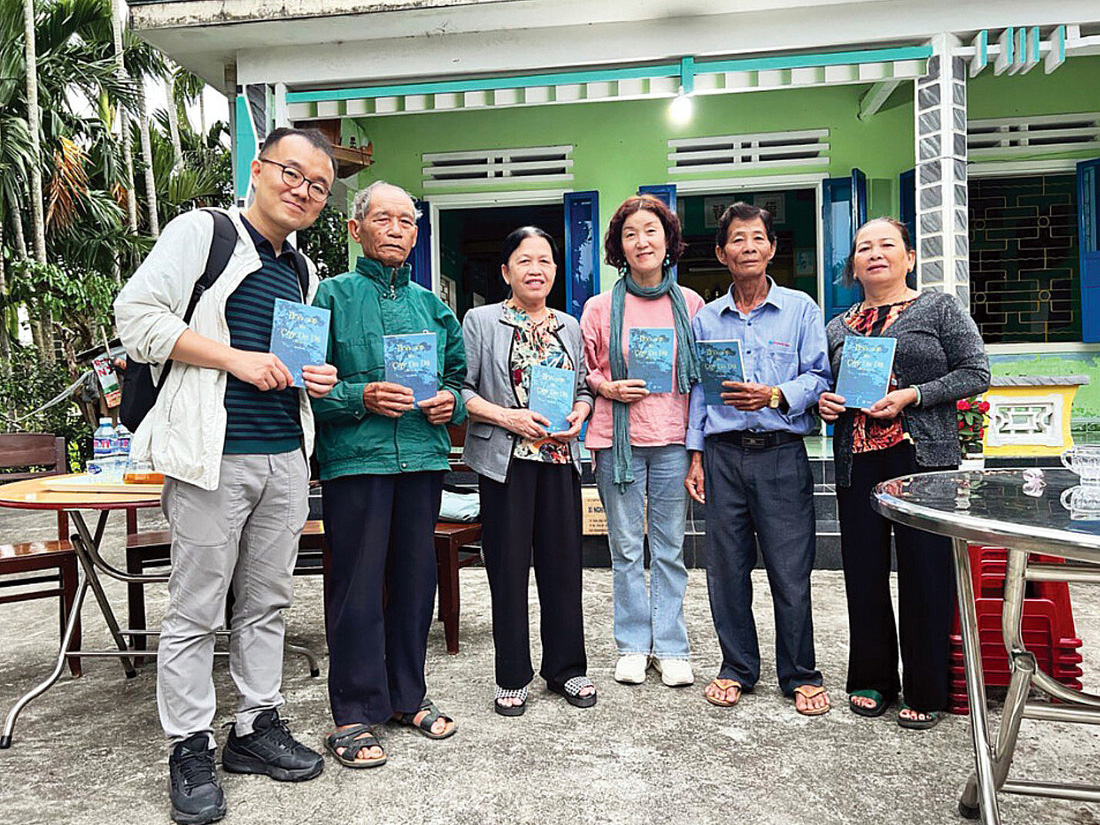 Đại diện Quỹ hòa bình Hàn - Việt cùng nhà văn Kim Yi Jeong tặng sách cho nạn nhân và thân nhân ở làng Phong Nhị - Ảnh: Quỹ hòa bình cung cấp