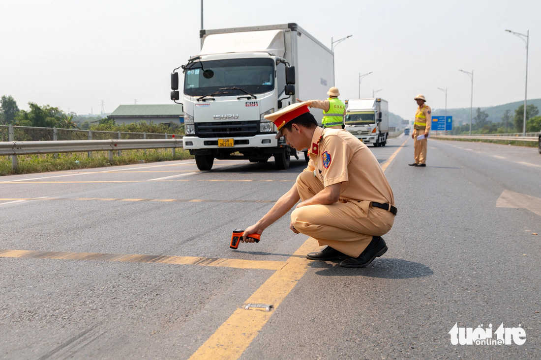 Cánh sát giao thông đo nhiệt độ mặt đường cao tốc Cam Lộ - La Sơn lúc 10h sáng 5-4 để đưa ra khuyến cáo an toàn phù hợp cho tài xế - Ảnh: HOÀNG TÁO