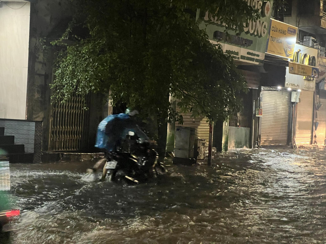 Người dân hì hục dắt xe máy qua khu vực ngập sâu - Ảnh: PHẠM TUẤN