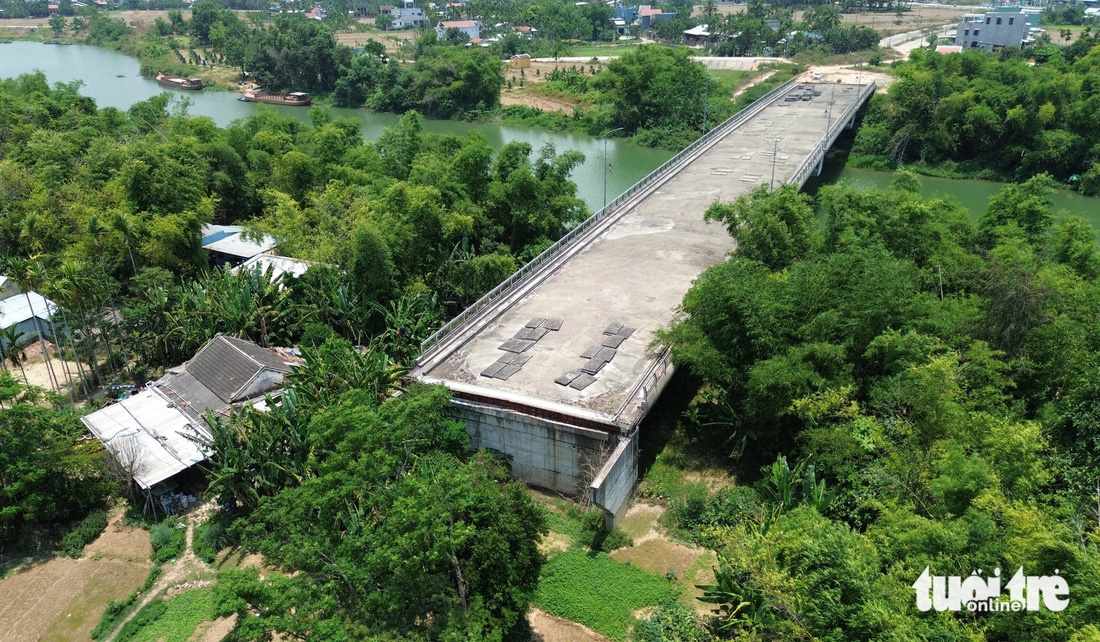 Phần đường dẫn cầu bắc qua sông Vĩnh Điện ở phía phường Điện Minh vẫn um tùm cây và nhà dân - Ảnh: LÊ TRUNG