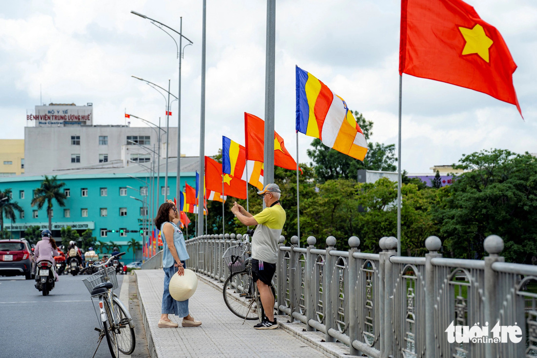 Du khách người nước ngoài dừng chân trên cầu Phú Xuân chụp ảnh lưu niệm và chụp ảnh bảy đóa sen khổng lồ trên sông Hương - Ảnh: LÊ ĐÌNH HOÀNG